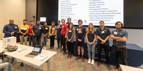 Participants, mentors, and organizers of the 2025 AI-HDL League standing together at the final presentation and award ceremony, with a screen listing participant names behind them.