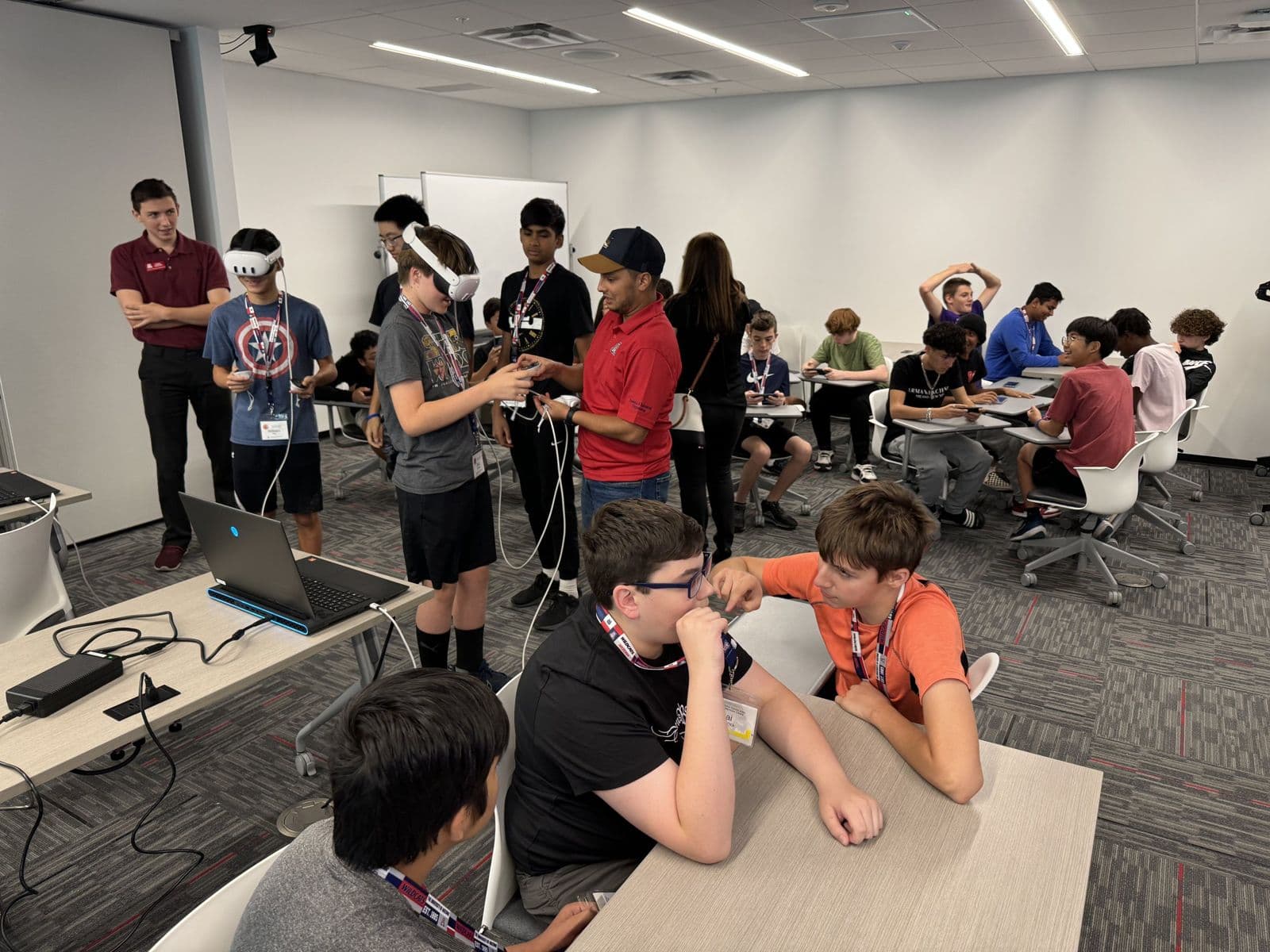 Classroom of summer camp students trying VR headsets and working at tables.