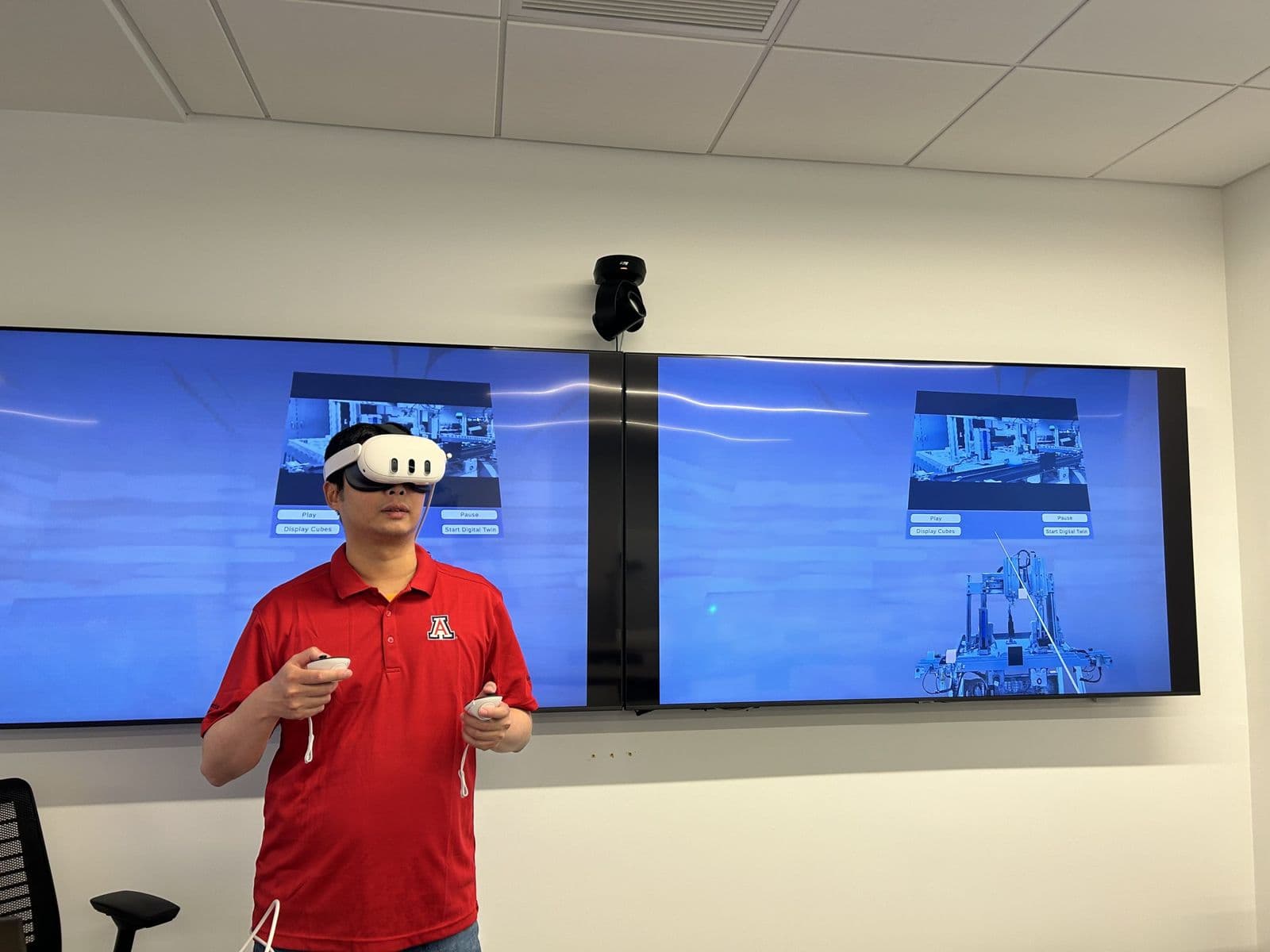 Sujan Ghimire wearing a VR headset in front of screens showing a virtual environment.
