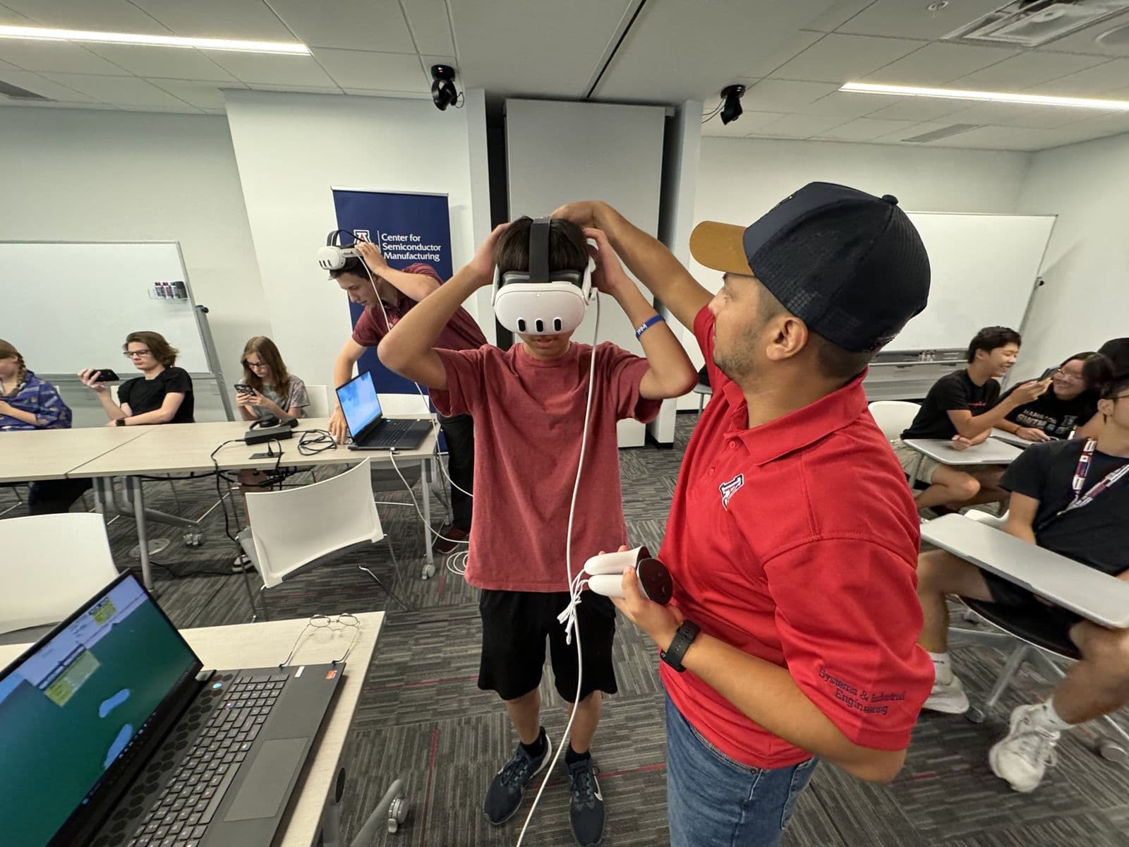 Sujan Ghimire helping a student put on a virtual reality headset in a classroom.