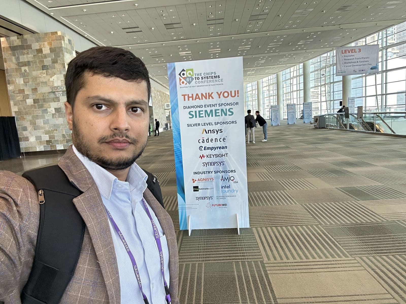 Selfie of Sujan Ghimire in the conference hall at the 61st Design Automation Conference, next to a sponsor sign.