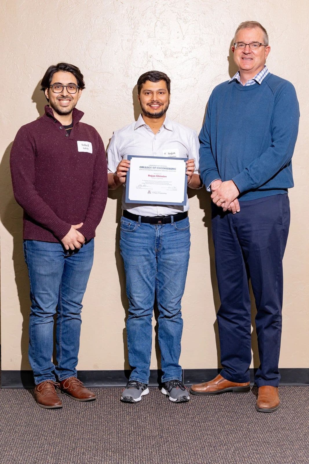 Sujan Ghimire holding the 2024 Outstanding Graduate Teaching Assistant certificate, standing between two colleagues.
