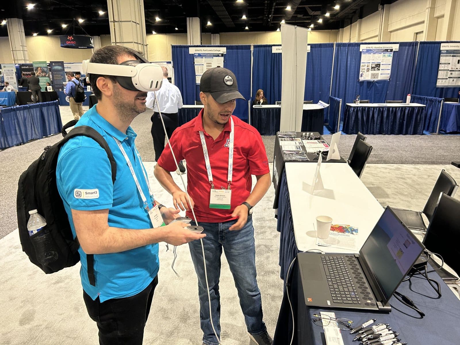 Sujan Ghimire guiding a conference attendee wearing a virtual reality headset at the exhibit booth.