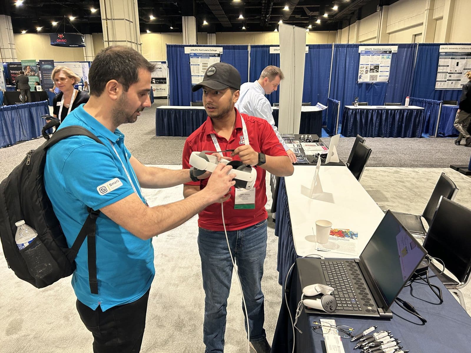 Sujan Ghimire handing VR controllers to a conference attendee at the exhibit booth.