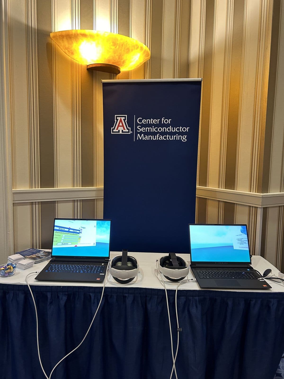 Center for Semiconductor Manufacturing exhibit table with laptops and virtual reality headsets.