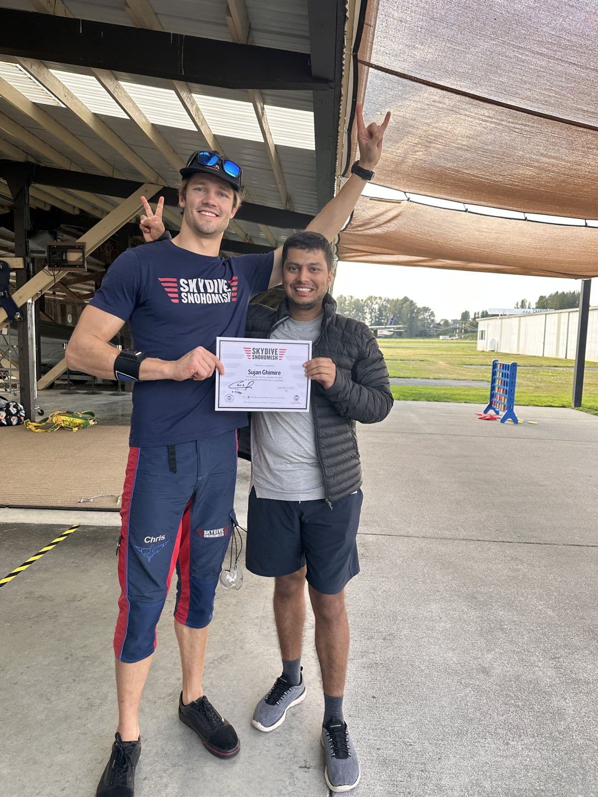 Sujan Ghimire and the skydiving instructor holding a certificate after landing.
